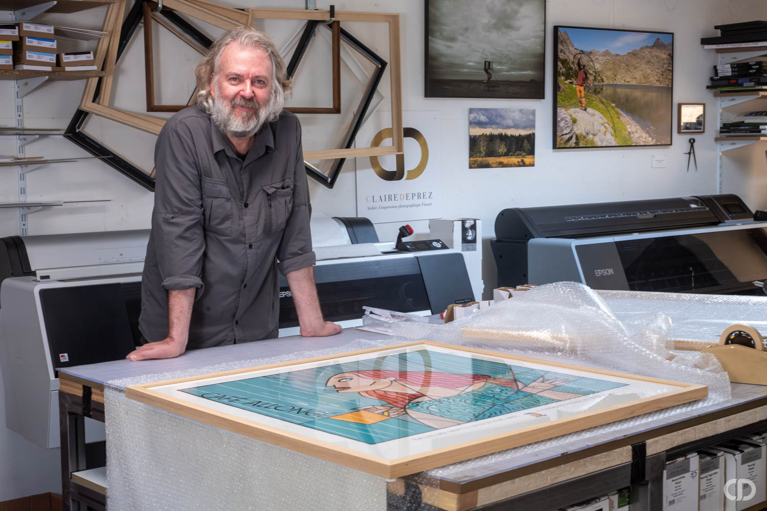 Artiste appuyé sur une table devant son oeuvre encadrée