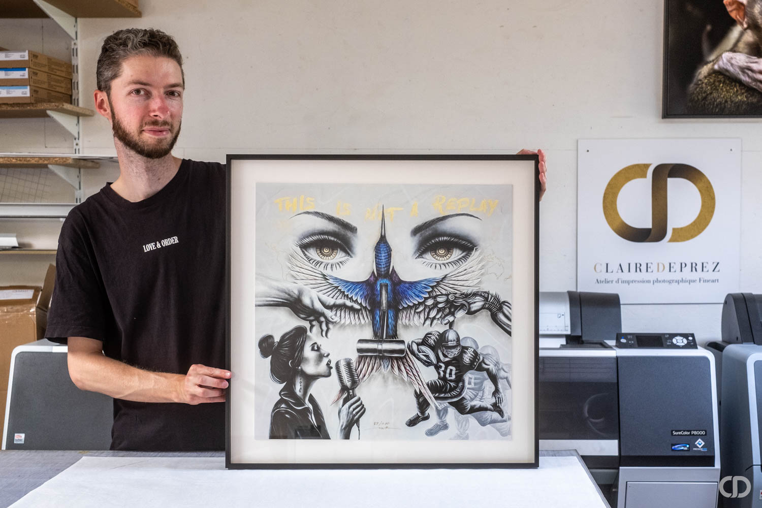 Artiste tenant son oeuvre encadrée sur la table